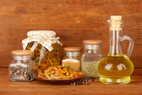 Composition of delicious marinated mushrooms, oil and spices on wooden table on wooden background — Stock Photo, Image