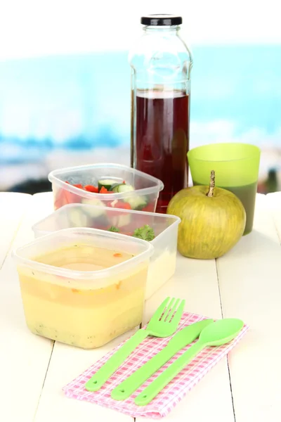 Tasty lunch in plastic containers, on wooden table on bright background — Stock Photo, Image