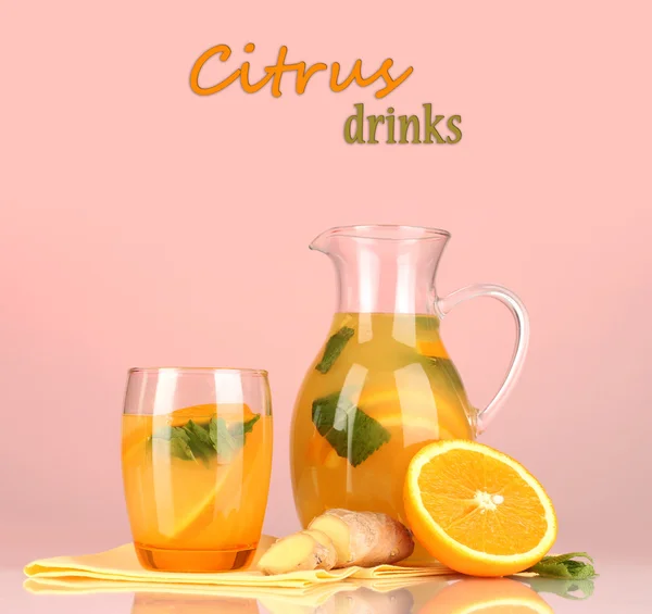 Oranje limonade in werper en glas op roze achtergrond — Stockfoto