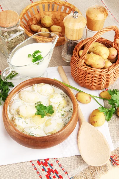 Zarte junge Kartoffeln mit saurer Sahne und Kräutern in hölzerner Schüssel auf Tischdecke in Großaufnahme — Stockfoto