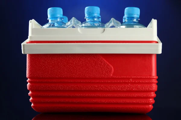 Frigorífico de viagem com garrafas de água e cubos de gelo, sobre fundo azul — Fotografia de Stock