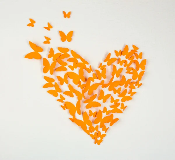 Бумажная оранжевая бабочка в форме сердца на стене — стоковое фото