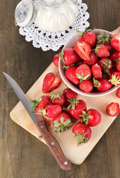 Fresas en cuenco a bordo corte en mesa de madera — Foto de Stock