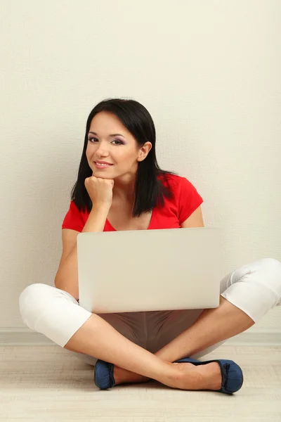 Bella giovane donna seduta con notebook in camera — Foto Stock