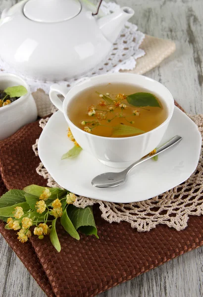 Kopp te med linden på servetter på träbord — Stockfoto