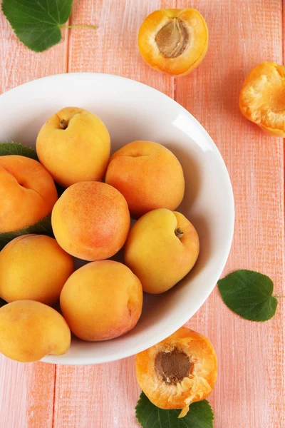 Apricots in plate on wooden table — Stock Photo, Image