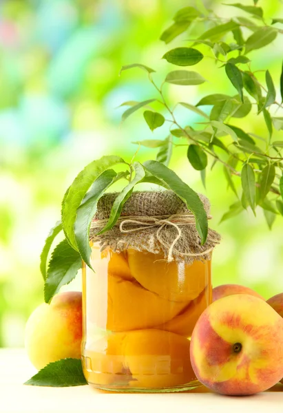 Burk konserverade persikor och färska persikor på träbord, utanför — Stockfoto