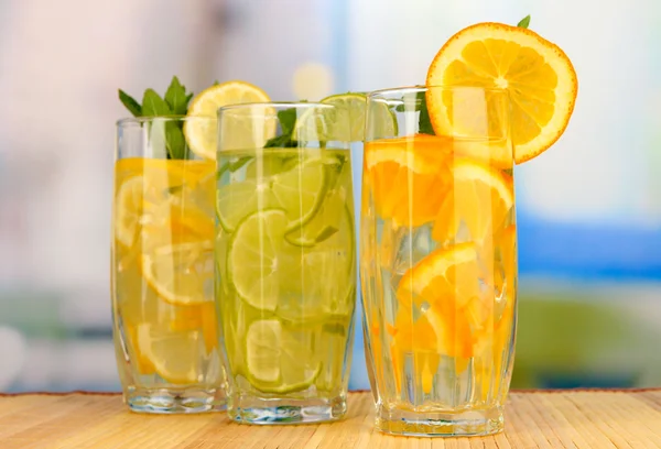 Glasses of fruit drinks with ice cubes on table in cafe — Stock Photo, Image