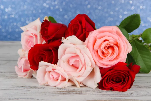 Beautiful bouquet of roses on table on blue background — Stock Photo, Image