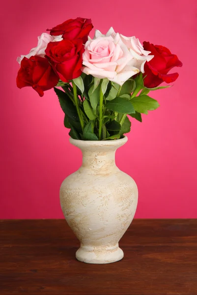 Beautiful bouquet of roses in vase with gift on table on pink background — Stock Photo, Image
