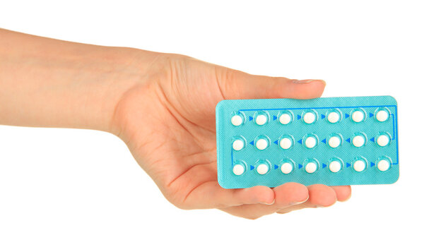 Hormonal pills in female hand isolated on white