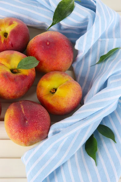 Peaches on napkin on wooden table — Stock Photo, Image