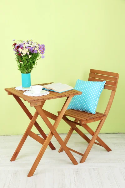 Holztisch mit Blume, Buch und Tasse darauf im Zimmer — Stockfoto