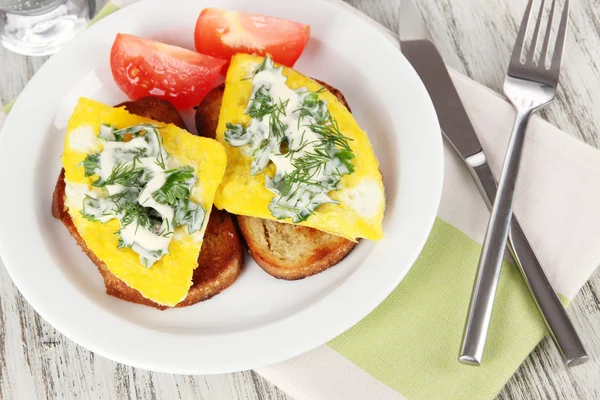 Äggröra och toast på plattan på servett på träbord — Stockfoto