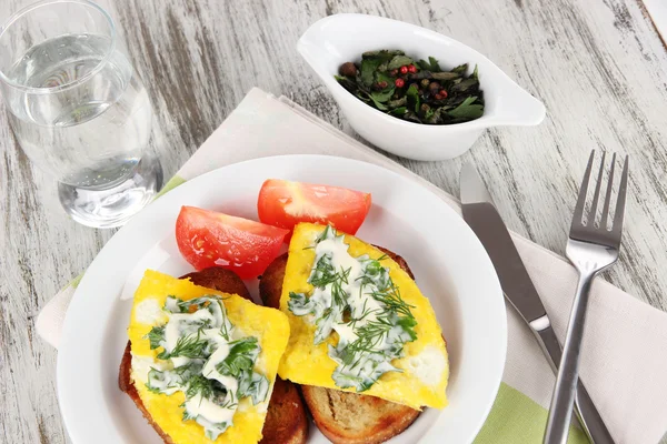 Äggröra och toast på plattan på servett på träbord — Stockfoto