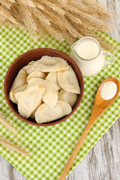 Tasty dumplings with fried onion on brown plate, on wooden background — Stock Photo, Image