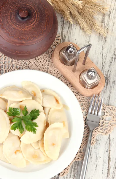 Smakelijke dumplings met gebakken UI op witte plaat, op houten achtergrond — Stockfoto