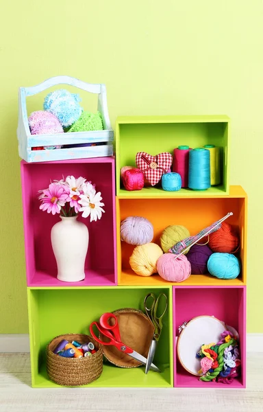 Kleurrijke schappen van verschillende kleuren met gebruiksvoorwerpen op muur achtergrond — Stockfoto