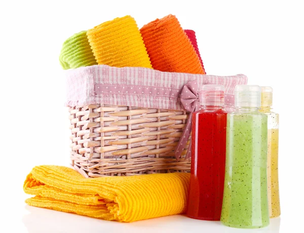 Colorful towels in basket and cosmetics bottles, isolated on white — Stock Photo, Image