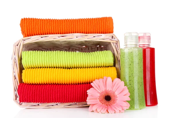 Colorful towels in basket and cosmetics bottles isolated on white — Stock Photo, Image