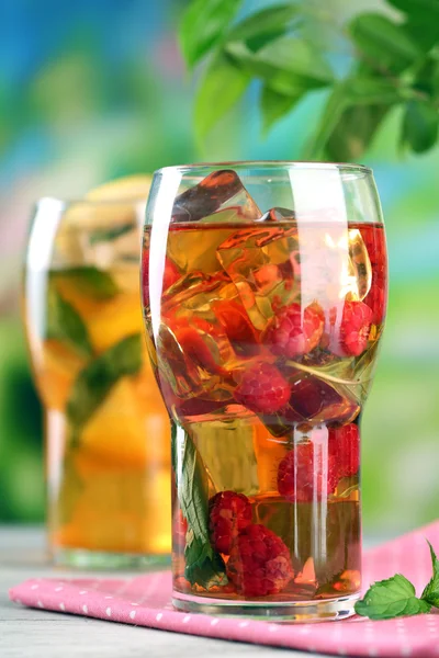 Iced tea with raspberries, lemon and mint on wooden table, outdoors — Stock Photo, Image