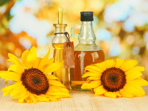 Oil in jars and sunflower on wooden table close-up — Stock Photo, Image