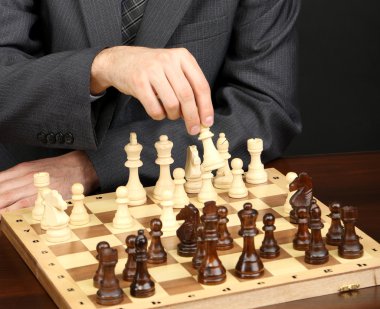 siyah arka plan üzerinde satranç oynayan genç iş adamı