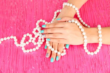 Mavi boncuk, renkli arka plan üzerinde tutarak manikür ellerle güzel kadın