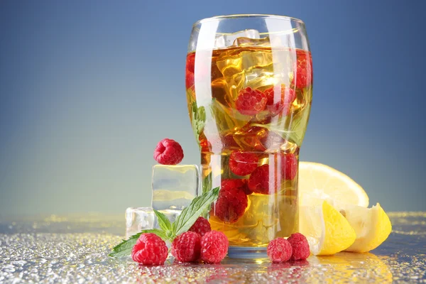 Iced tea with raspberries and mint on blue background — Stock Photo, Image