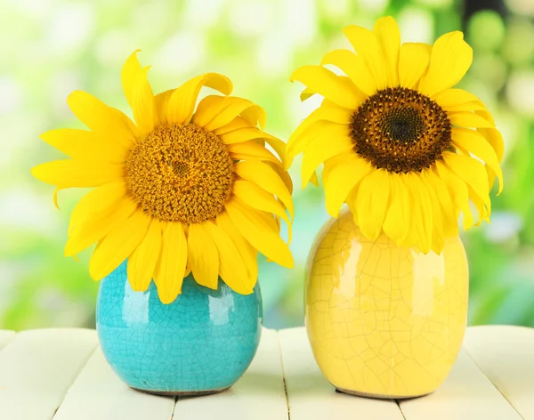 Heldere zonnebloemen in vaas op houten tafel op natuurlijke achtergrond — Stockfoto