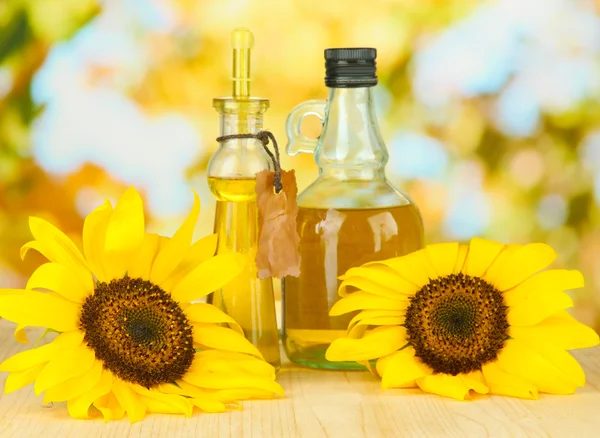 Öl in Gläsern und Sonnenblumen auf Holztisch in Großaufnahme — Stockfoto