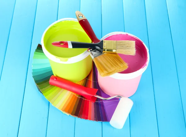 Set for painting: paint pots, brushes, paint-roller on blue wooden table — Stock Photo, Image