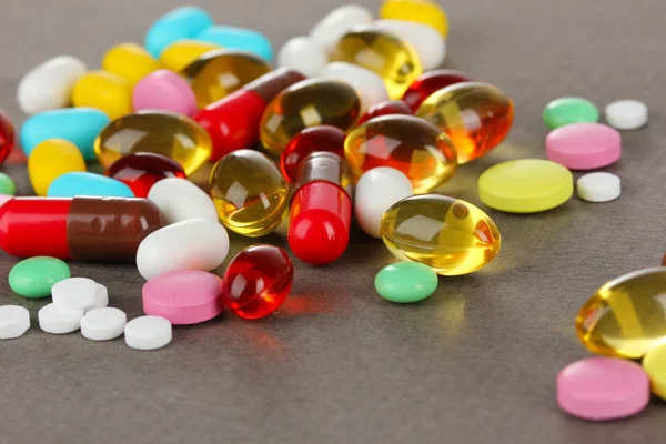 Surtido de pastillas, comprimidos y cápsulas sobre fondo gris — Foto de Stock
