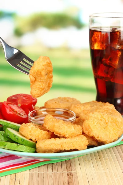 Fried chicken nuggets with vegetables,cola and sauce on table in park — Stock Photo, Image