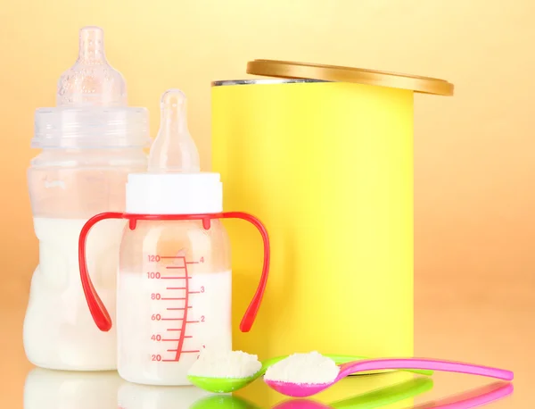 Bottles with milk and food for babies on beige background — Stock Photo, Image