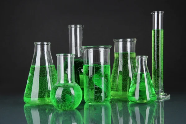 Тестовые трубки с зеленой жидкостью на темно-сером фоне — стоковое фото