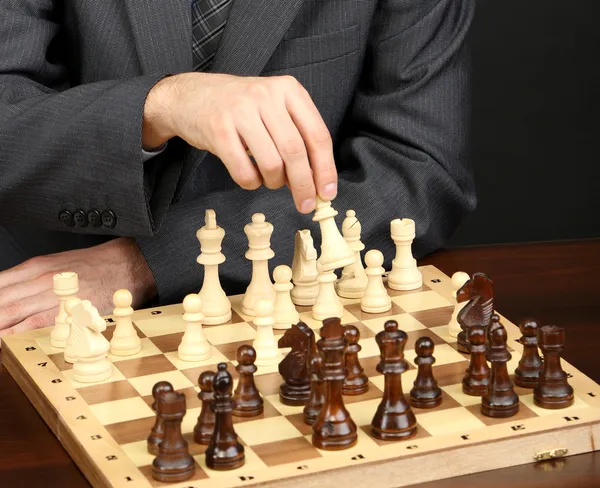 Junger Geschäftsmann spielt Schach auf schwarzem Hintergrund — Stockfoto