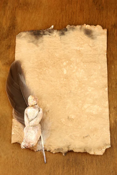 Papel viejo con figurilla, sobre fondo de madera — Foto de Stock