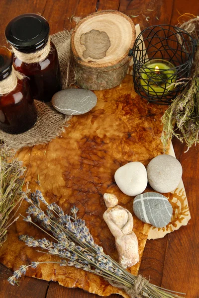 Composition with old papers, herbs, stones and bottles with symbols on wooden background — Stock Photo, Image