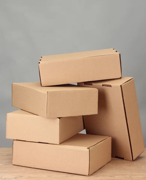 Parcels boxes on wooden table, on grey background — Stock Photo, Image