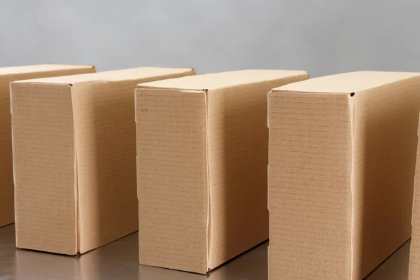 Cardboard boxes on conveyor belt, on grey background — Stock Photo, Image