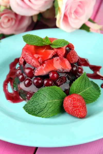 Смачний желе-десерт зі свіжими ягодами, на фоні рожевих троянд — стокове фото