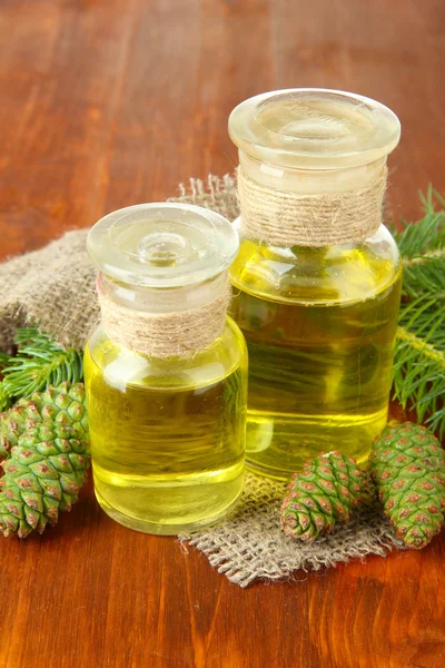 Flaskor av fir tree olja och gröna kottar på trä bakgrund — Stockfoto