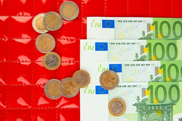 Euro banknotes and euro cents on red background — Stock Photo, Image