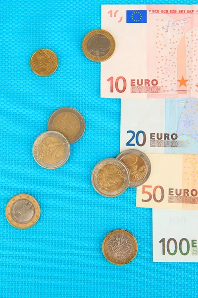 Eurobankovky a euro centů na modrém pozadí — Stock fotografie