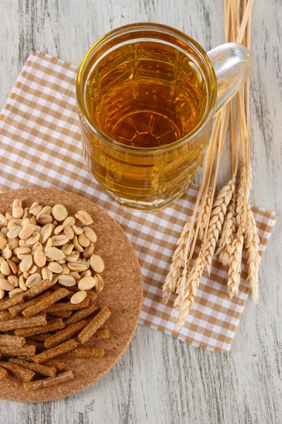 Beer in glass crunches, and nuts on napkin on wooden table — Stock Photo, Image