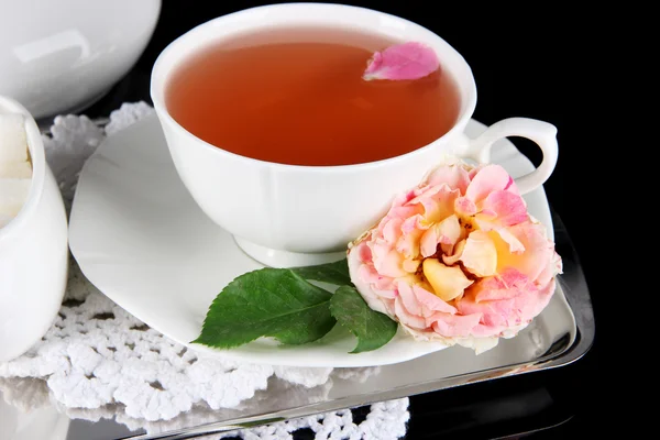 Cup of tea from tea rose on metallic tray on napkin black background — Stock Photo, Image