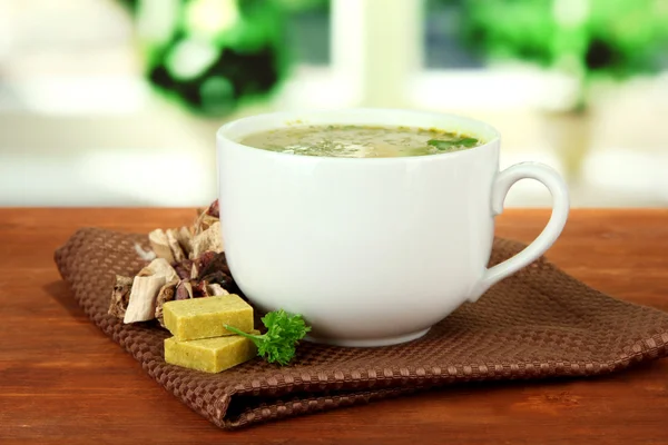 Cup of soup with bouillon cubes on wooden table — Stock Photo, Image
