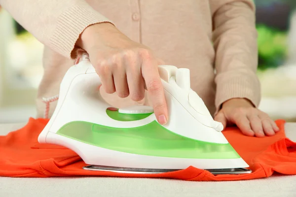 Woman's hand ironing clothes, on bright background — Stock Photo, Image