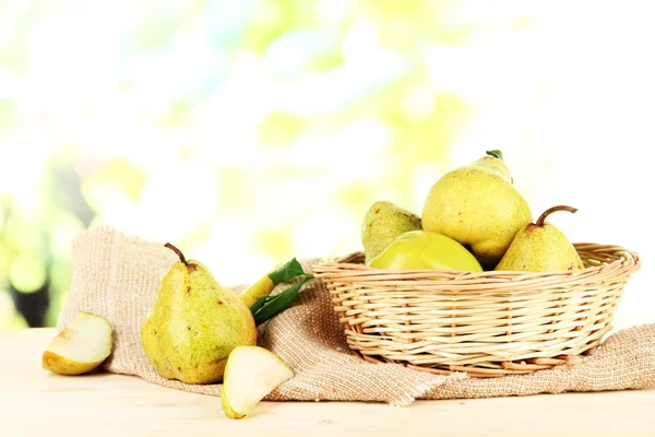 Pears in basket on burlap on wooden table on nature background — Stock Photo, Image